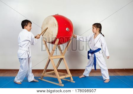 Two children in a kimono pounding the drum. Fighting position active lifestyle practicing fighting techniques