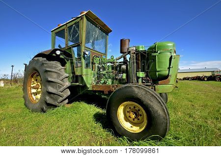 A tractor with a cab missing an engine is left for parts, salvage and scrap iron.