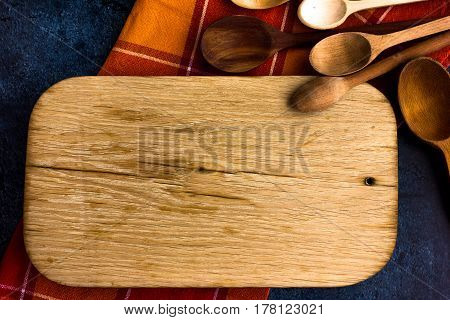 Rural kitchen board  With wooden spoons and old red cloth from above - grunge background with free text space. concrete background.  Different stuff. Top view.