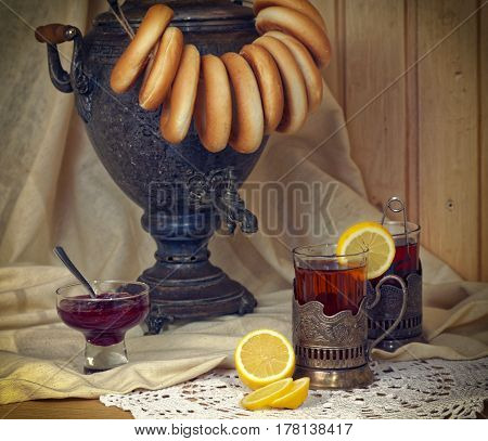 Russian samovar, tea with lemon in faceted glasses with cup holders and bublik. Tinted photo in vintage style.