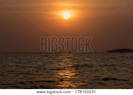 The sun sets as a flotilla of fishing boats head out to sea.