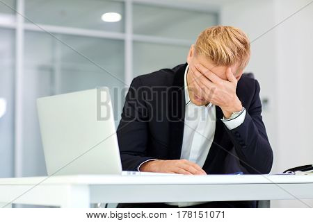 The concept stress crisis depression failure in business. Businessman covered his face with his hand at  table with  laptop I got  office.