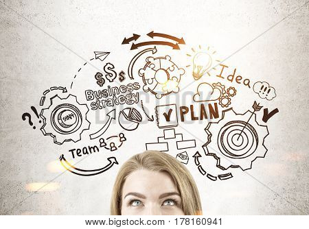 Close up of a head of a blond woman standing near a concrete wall with a business plan sketch drawn on it toned image.
