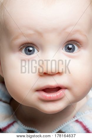 happy baby boy little child with blond hair and big eyes on adorable surprised face has cute cheeks childhood and happiness