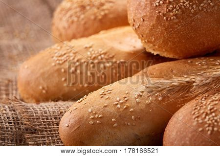 Freshly baked baguette bread and rulls on a burlap napkin on a wooden background. Close up. Delicious food. Fresh baking. Tasty and appetizing.