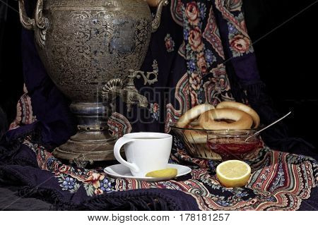 Russian samovar, tea cup with lemon and bublik. Tinted photo in vintage style on black background.