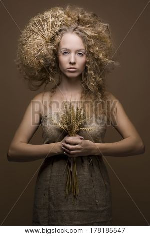 portrait of beautiful curly girl with wheat on a beige background