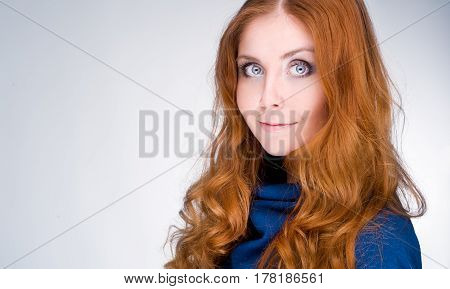 studio portrait of pretty redhead girl on a light background.