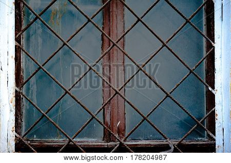 Old window with an rusty grating on a old wall with bricks