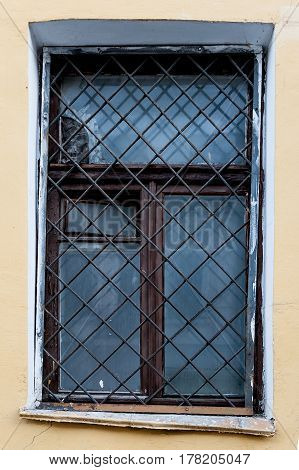 Old window with an rusty grating on a old wall with bricks
