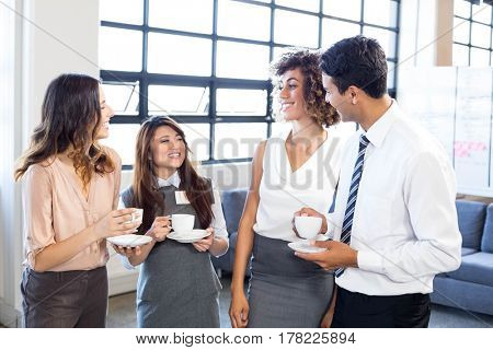Businesspeople having tea and interacting during breaktime in office