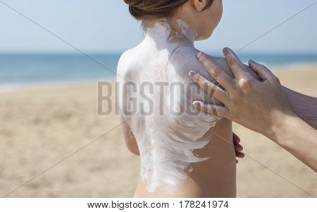 Mother applying sunblock cream to her daughter on shoulder El Rompido Huelva Spain