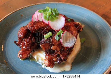 Simple blue dish with alligator legs cooked to perfection, garnished with
sliced radishes and tangy-sweet dipping sauce