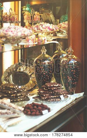Rich variety of chocolates and candies in display window of italian pastry shop at sunny day at the street of Florence
