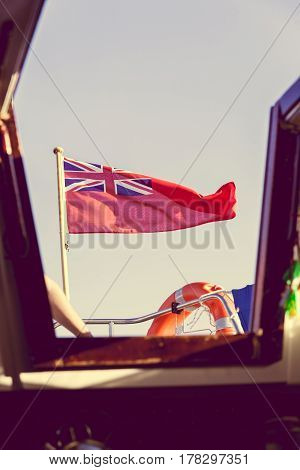 The uk red ensign the british maritime flag flown from yacht sail boat blue sky and baltic sea. Summer and travel voyage