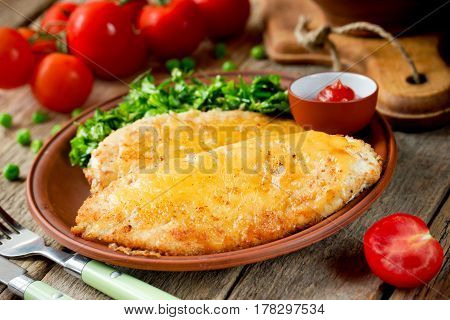 Turkey breast chops cutlets with cheese crust and fresh vegetable on garnish