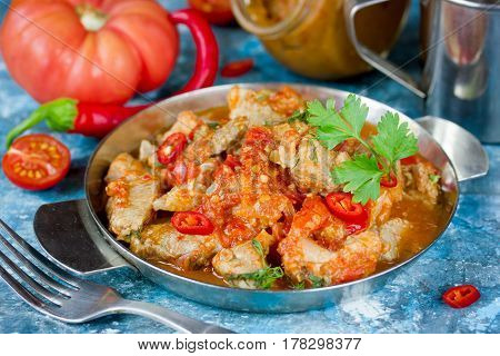 Canned stewed pork meat in red pepper tomato sauce