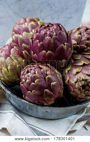 Fresh big Romanesco artichokes green-purple flower heads ready to cook seasonal food