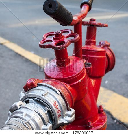 Red fire hydrant with connected hose. Close-up.