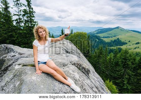 Beautiful woman hiker taking photo with cellphone on mountain top