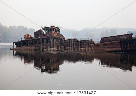 Old rusty sunken ship in water in a foggy day.