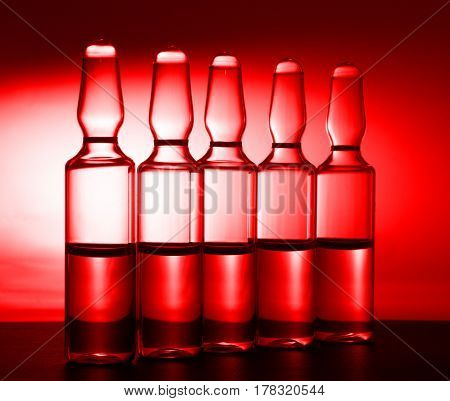 Row of ampulas with medicine on red background