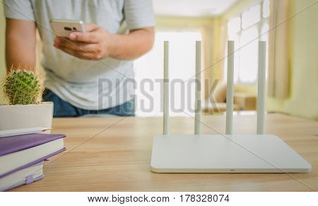 closeup of a wireless router and a man using smartphone on living room at home ofiice
