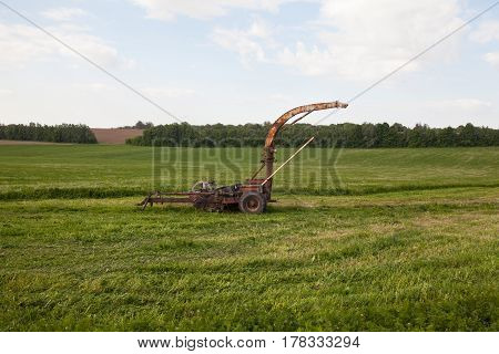 Old rusty mower on the newly mown grass in the field. Agricultural machinery.