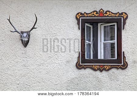 bavarian rural window with typical painted frame decorations and vintage deer antler on old wall