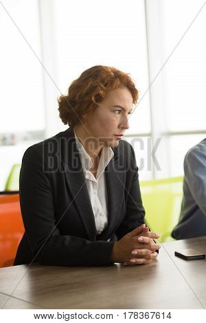 Angry business woman working as boss in building company. Pretty red haired lady going to employ new workers to her company. Aggressive lady looking away.