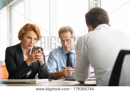 Business people having negotiations with new business partner. Business man and woman looking at man sitting in front. Deal concept. Company partnership concept.