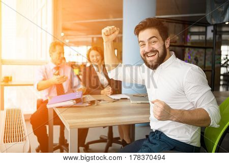 Toned of young businessman looking happy after successful interview to huge company. Bearded man looking at camera and smiling. Office concept. Interview concept.