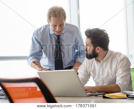 Mobbing, stress, work, scandal concepts. Angry boss man explaining his worker new business strategy while he is working on laptop computer.