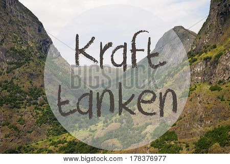German Text Kraft Tanke Means Relax. Valley With Mountains In Norway, Peaceful Landscape Scenery With Grass, Trees And Rocks.