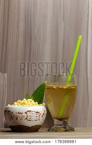 A glass of a summer drink Jal zeera or cumin lemonade with spices and chickpea flour balls on a wooden background selective focus.