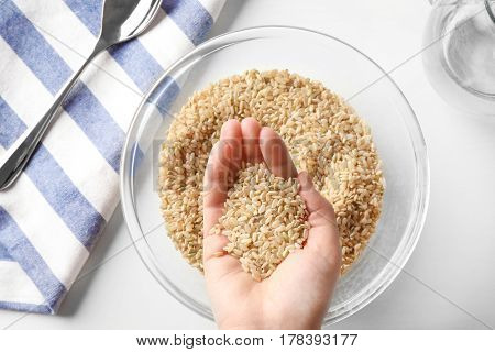Handful of brown rice taken from glass bowl