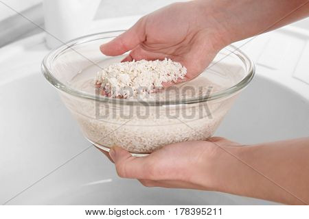 Woman rinsing rice in glass bowl with water