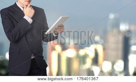 Double Exposure Confident Asian Businessman Reading Notebook Or Document File With Cityscape On Blur