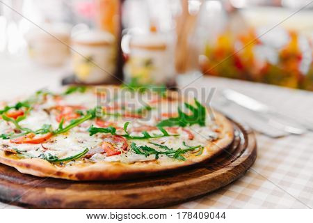 Pizza with cheese, tomato and meat, on served table with plaid tablecloth
