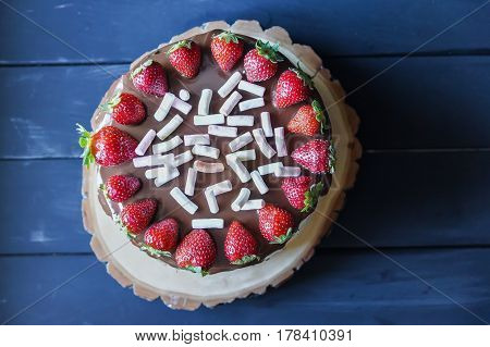 Delicious cake with fresh strawberry and dark chocolate sauce and plate with marshmallows, top view