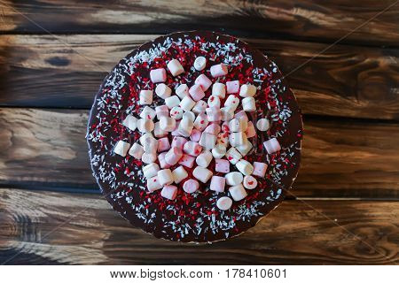 Delicious cake with dark chocolate sauce and with marshmallows, top view