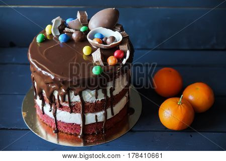 Beautiful cake with m-n-m, kinder, chocolate sauce and peace of chocolate, with tangerines near