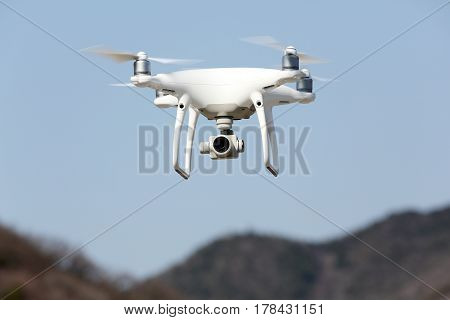 KAGAWA, JAPAN - MARCH 17, 2017: White remote controlled Drone Dji Phantom4 Pro equipped with high resolution video camera hovering in air and blue sky in the background