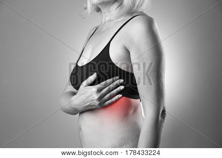 Breast test woman examining her breasts for cancer heart attack pain in human body black and white photo with red spots