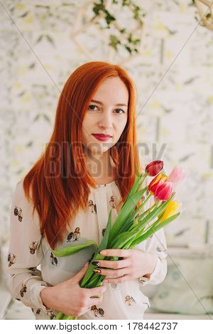 red-haired girl holding a bouquet of tulips