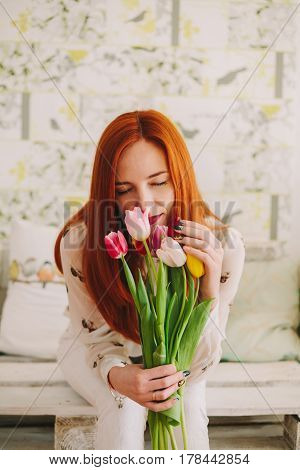 red-haired girl sniffing a bouquet of tulips