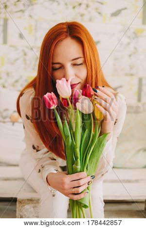 red-haired girl sniffing a bouquet of tulips
