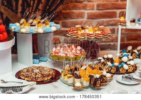 blue white sweets on gilded paper on the wedding candybar. Brick wall on a background.