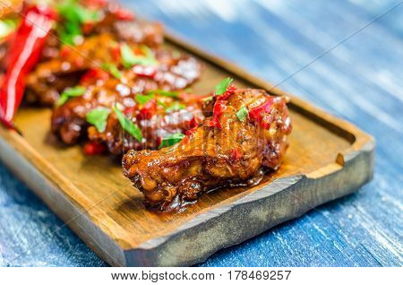 Hot meat dish - Fried chicken legs with curry sauce and red pepper on a wooden board