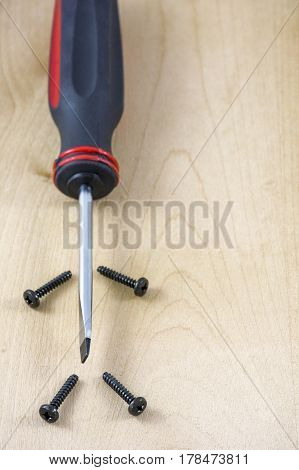 Screwdriver with several screw as a man on wooden background